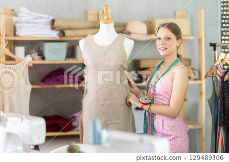 Woman seamstress adjusts clothes on mannequin 129489306