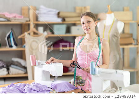 Young woman seamstress posing in sewing workshop Young woman seamstress posing in sewing workshop 129489314