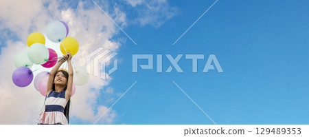 Banner Cheerful cute girl holding balloons running green meadow white cloud and blue sky with happiness. Panorama Hands holding vibrant air balloons happy times summer sunlight outdoor copy space Banner Cheerful cute girl holding balloons running green meadow white cloud and blue sky with happiness. Panorama Hands holding vibrant air balloons happy times summer sunlight outdoor copy space 129489353