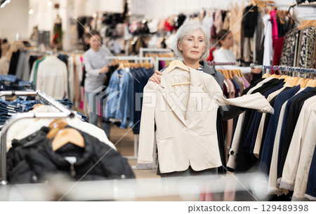 Old woman choosing convenient blazer in clothing store 129489398