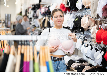 Young woman choosing pretty bra in underwear store 129489427