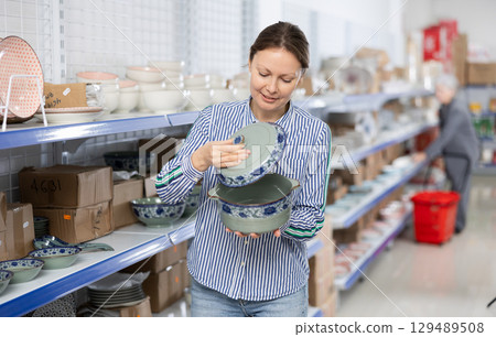 Cheerful female shopper choosing ceramic soup tureen at Asian store 129489508