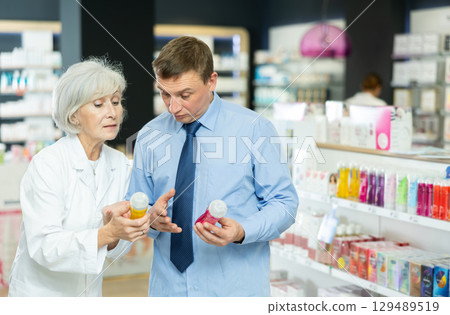 Middle-aged man choosing lubricant with help of old pharmacist 129489519