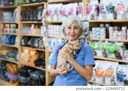 Senior woman veterinarian is standing with dog Chihuahua in pet store pharmacy. 129489712