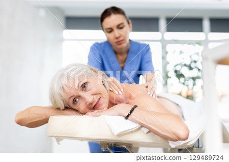 Elderly woman satisfied with work of masseuse Elderly woman satisfied with work of masseuse 129489724