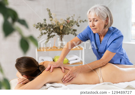 Unrecognizable young woman lies face down and enjoy shoulder massage for body care Unrecognizable young woman lies face down and enjoy shoulder massage for body care 129489727