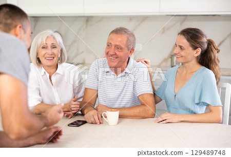 Family of four sits at table and talking Family of four sits at table and talking 129489748