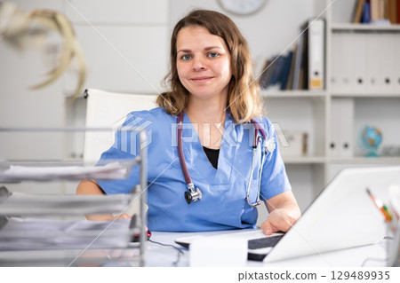 Portrait of female doctor who is working with laptop and documents Portrait of female doctor who is working with laptop and documents 129489935