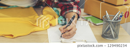 Fashion designer Women measure clothing design packing box on table. Women checking goods size, quality to delivery box package. Entrepreneur Asian woman startup small business at home office desk 129490234
