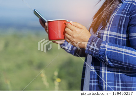 Close up Woman hand holding black coffee cup in green garden cafe. Hands of businesswoman love drinking hot coffee. business women with black coffee or hot chocolate in coffee shop. Caffeine drinking 129490237