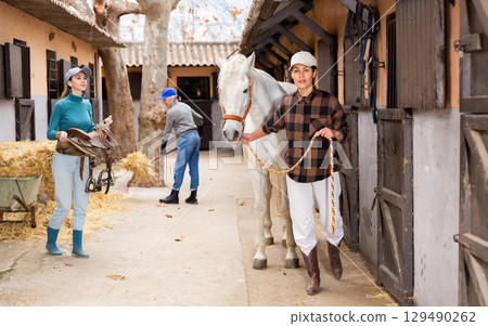 Women ranchers preparing white horse for ride Women ranchers preparing white horse for ride 129490262