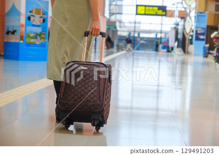 Woman walking with luggage at airport, traveler, tourist Woman walking with luggage at airport, traveler, tourist 129491203
