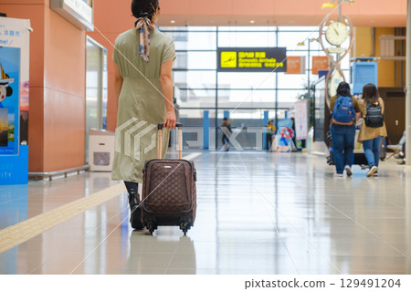 Woman walking with luggage at airport, traveler, tourist Woman walking with luggage at airport, traveler, tourist 129491204