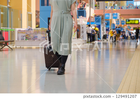 Woman walking with luggage at airport, traveler, tourist Woman walking with luggage at airport, traveler, tourist 129491207