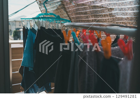 A family drying laundry in a small space inside a sunshade A family drying laundry in a small space inside a sunshade 129491281