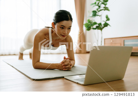 Young Asian woman in sportswear doing plank on training mat 129491813