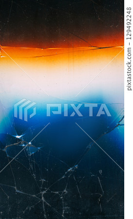 Fractured monitor. Crashed glass. Blue white orange spectrum colorful light glow on cracked black background abstract blur free space. 129492248