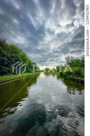 Gaze at the serene reflections on the river framed by stunning clouds, creating a picturesque scene Gaze at the serene reflections on the river framed by stunning clouds, creating a picturesque scene 129492965