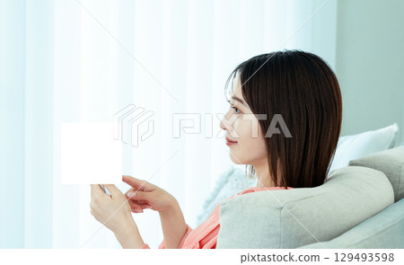觀看在沙發的一位小姐一個智能手機 129493598