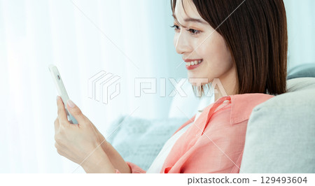觀看在沙發的一位小姐一個智能手機 129493604