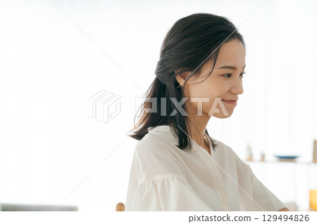一位 30 多歲的女士坐在客廳裡微笑 129494826