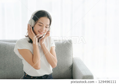 婦女在客廳裡聽音樂 婦女在客廳裡聽音樂 129496111