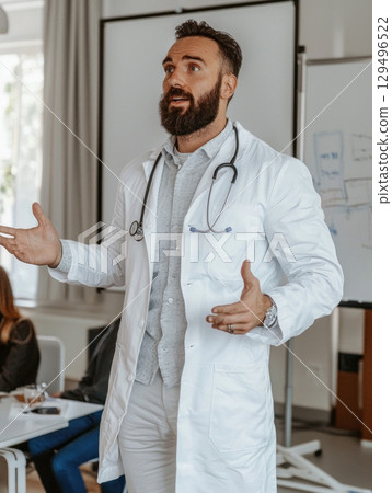 doctor in white coat with stethoscope speaks passionately during presentation 129496522