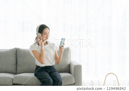 Woman listening to music on smartphone Woman listening to music on smartphone 129496842