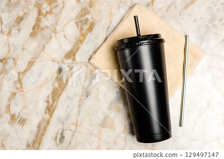 Black reusable cup with straw on marble surface and beige napkin for sustainable lifestyle 129497147