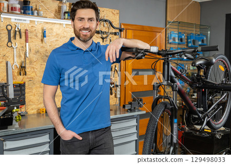 Confident man near mountain bike in home-based mechanical setting Confident man near mountain bike in home-based mechanical setting 129498033