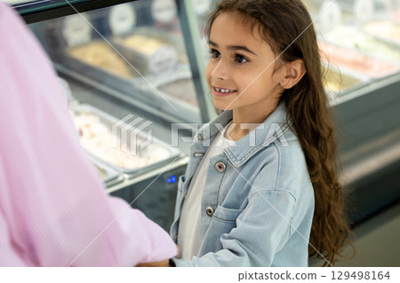 Woman and little girl with long curly hair choosing frozen desserts 129498164