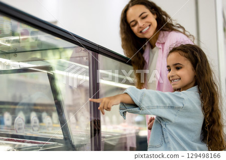 Smiling mother and daughter choosing ice cream in modern dessert shop Smiling mother and daughter choosing ice cream in modern dessert shop 129498166