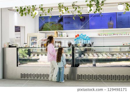 Young mom with daughter shopping for ice cream in modern cafe Young mom with daughter shopping for ice cream in modern cafe 129498171