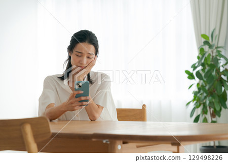 A woman with a depressed expression using a smartphone 129498226