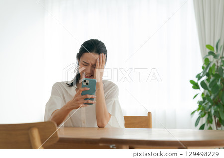 A woman with a depressed expression using a smartphone 129498229