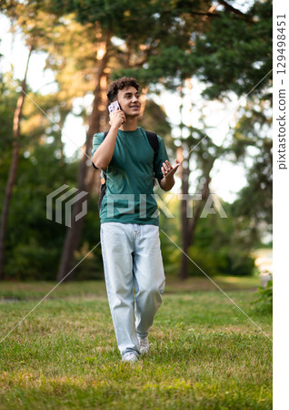 Dark-haired teen smiling and talking on the phone Dark-haired teen smiling and talking on the phone 129498451