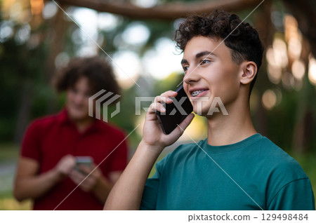Teens with phones in hands spending time together in the park 129498484