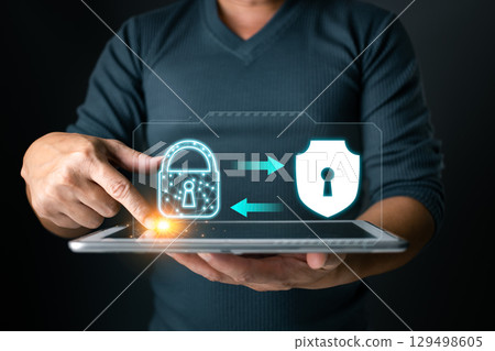Secured connection. A user interacts with a tablet displaying a lock and shield, symbolizing secure data transfer and protection against cyber threats. 129498605