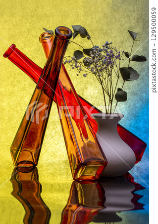 Still life with colored bottles and a vase of flowers Still life with colored bottles and a vase of flowers 129500059
