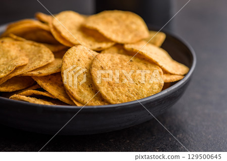 Crispy potato chips in bowl on black table. Crispy potato chips in bowl on black table. 129500645