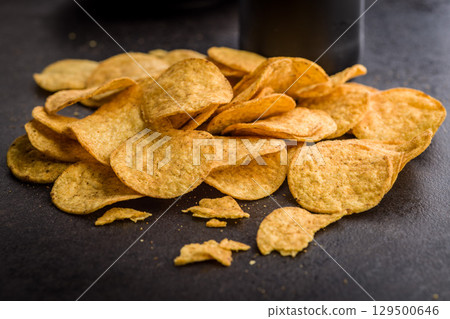 Crispy potato chips on black table. Crispy potato chips on black table. 129500646