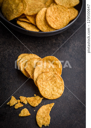 Crispy potato chips on black table. Crispy potato chips on black table. 129500647