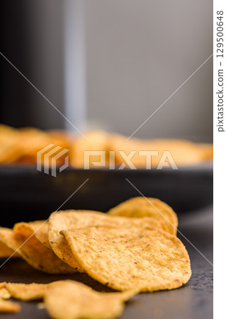 Crispy potato chips on black table. Crispy potato chips on black table. 129500648