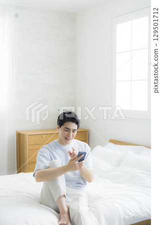 Men watching smartphones in bed 129501712