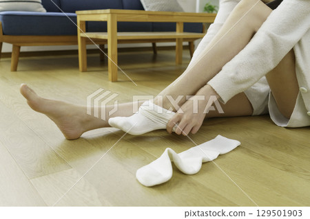 特寫鏡頭：一位年輕女子坐在客廳地板上穿著襪子 129501903