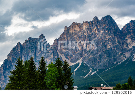 A panoramic view of the picturesque town of Cortina d'Ampezzo, nestled in the heart of the Dolomites. Majestic mountains rise in the background, offering a stunning natural backdrop. 129502016
