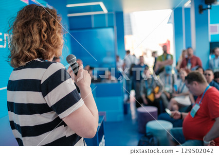 Speaker addressing an audience during a professional event in modern setting 129502042