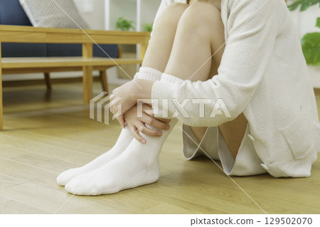 Close-up of a young woman's feet warming herself while sitting on the floor in the living room Close-up of a young woman's feet warming herself while sitting on the floor in the living room 129502070