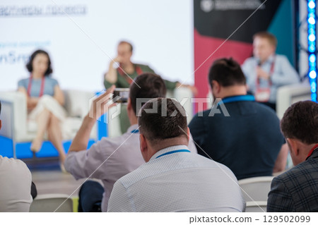 Attendees recording and watching a professional business conference event 129502099