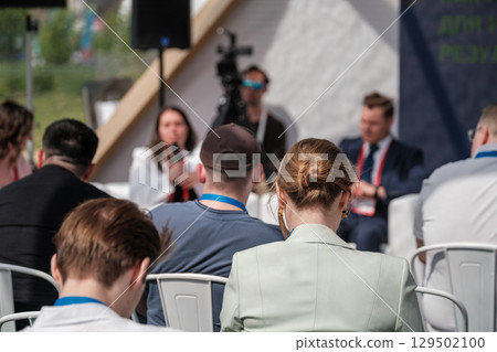 Participants attending an outdoor panel discussion with speakers and audience members engaged 129502100